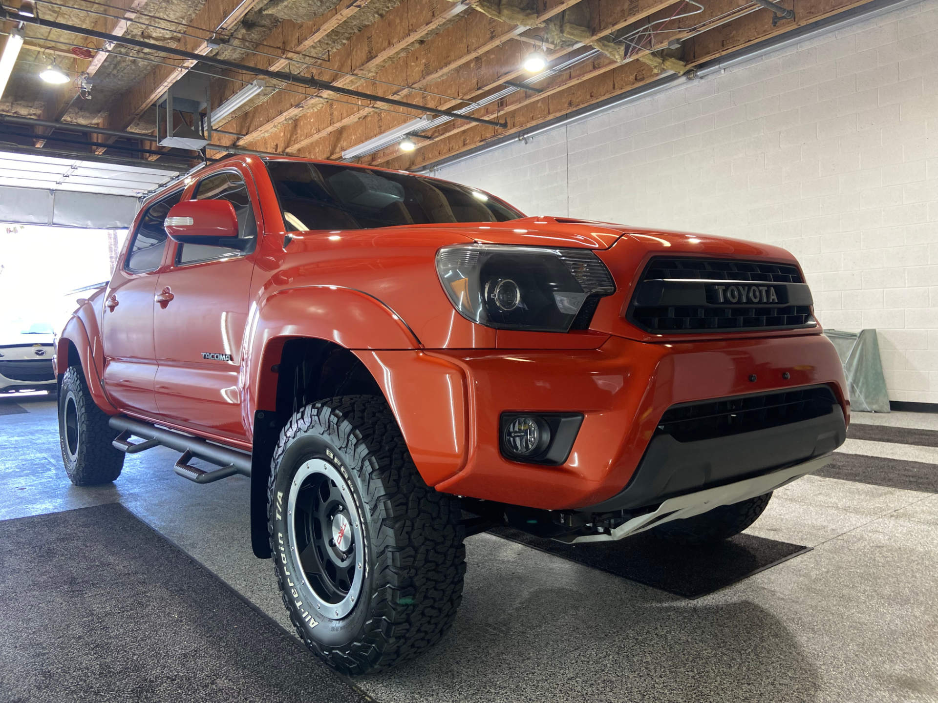 A red toyota tacoma truck is parked in a garage.