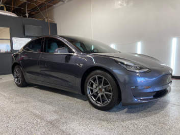 A tesla model 3 is parked in a garage.