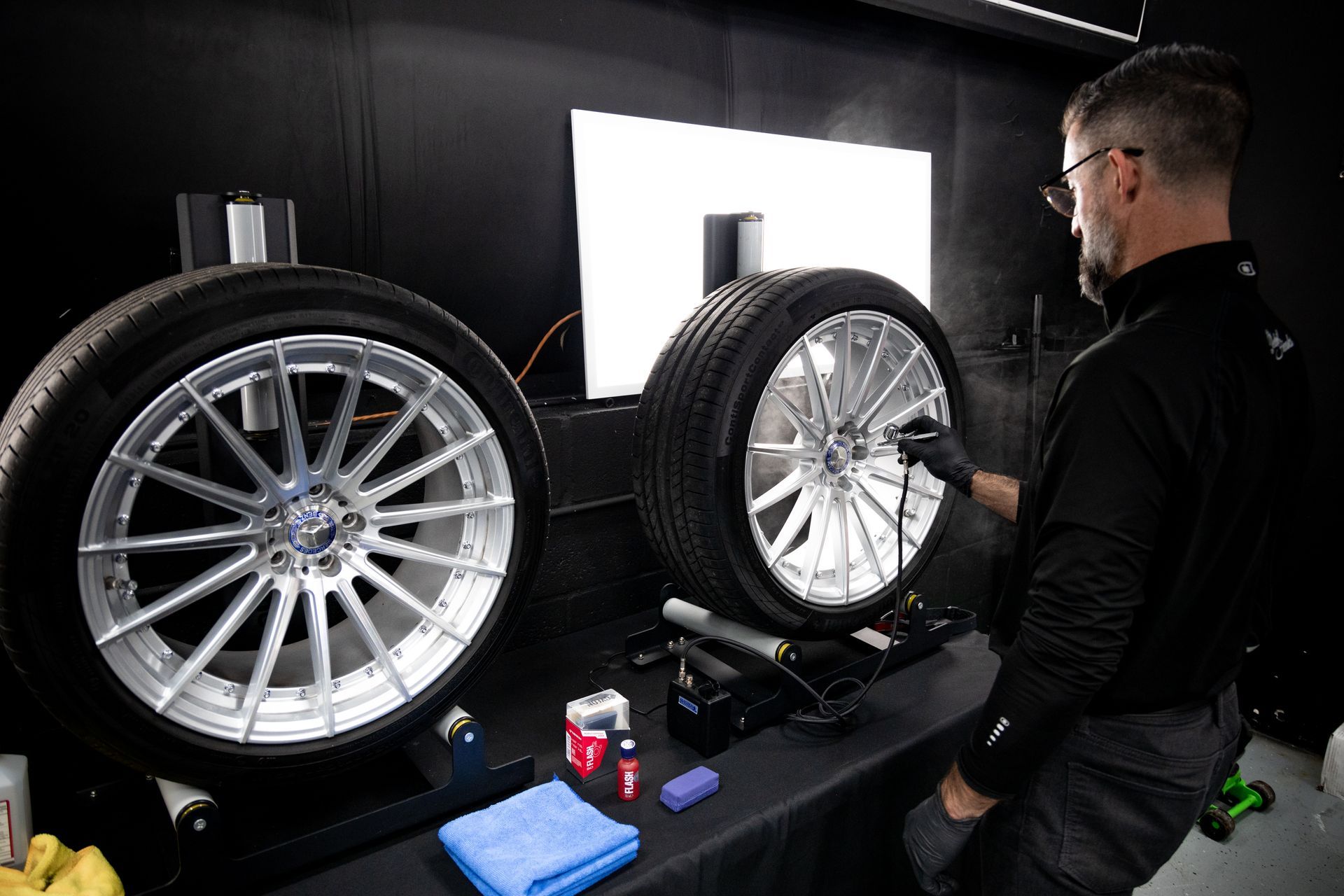 A man is working on a car wheel in a garage.
