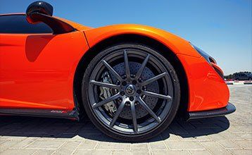 A close up of the front wheel of an orange sports car.