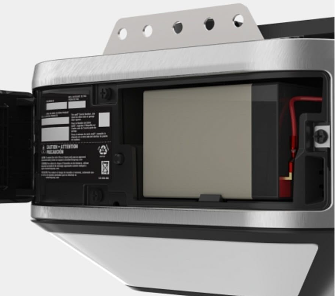 Garage door opener with a battery backup compartment open, showing the battery.