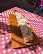 Pane con formaggio su un tagliere di legno sopra una tovaglia a quadri rosa.