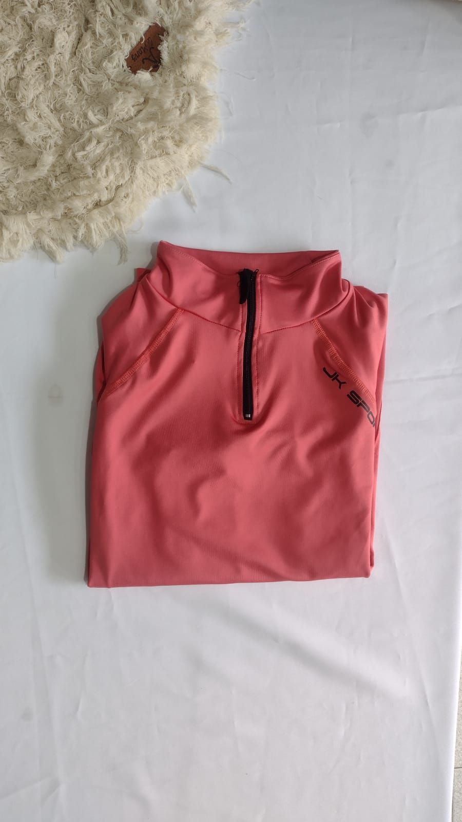 Camisa de manga larga, doblada, de color coral, con cierre de cremallera