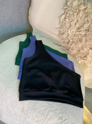 Tres crop tops están apilados uno encima del otro en una silla.