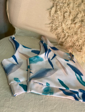 Un top corto blanco y azul está sobre una silla al lado de una almohada.