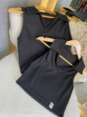 Dos camisas negras cuelgan en perchas de madera en una silla.