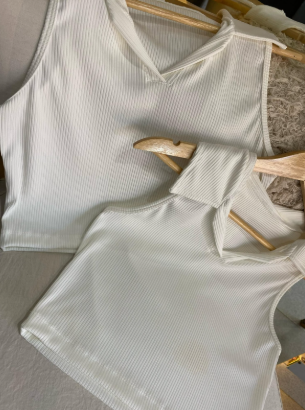 Dos camisas negras cuelgan en perchas de madera en una silla.