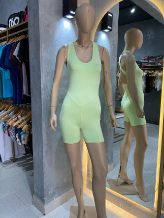 Un maniquí vestido con un mono verde está de pie frente a un espejo.