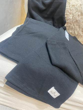 Una bufanda negra yace sobre una cama junto a una almohada.