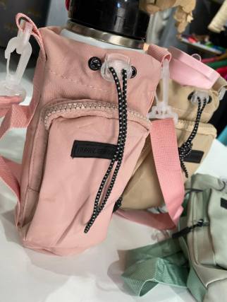 Un bolso rosa con una correa está sobre una mesa.