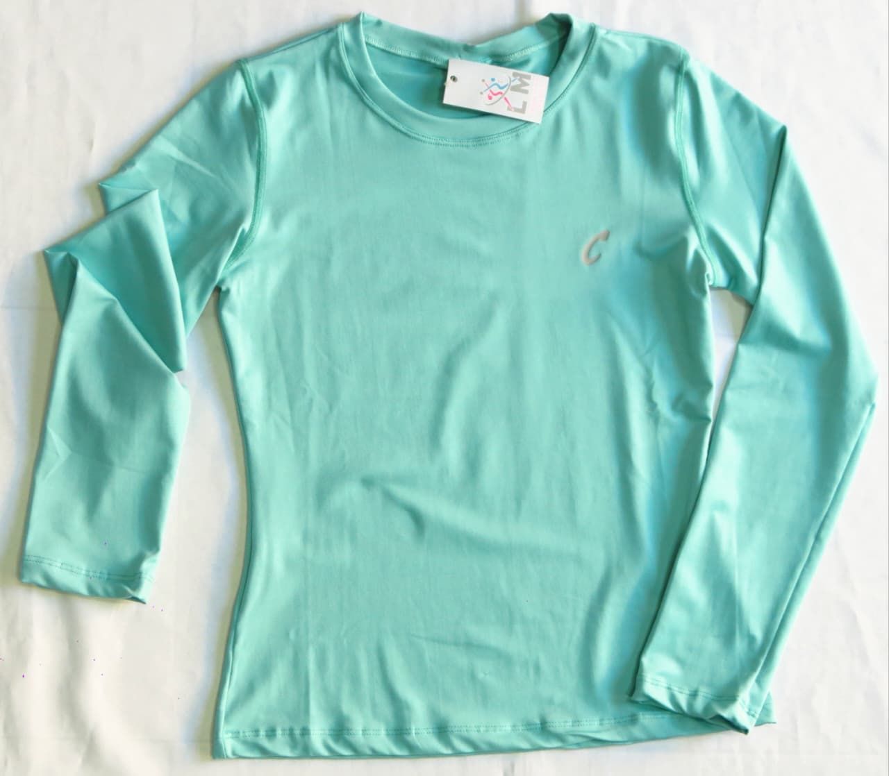 Camisa de manga larga de color verde azulado con un pequeño emblema cerca del pecho.