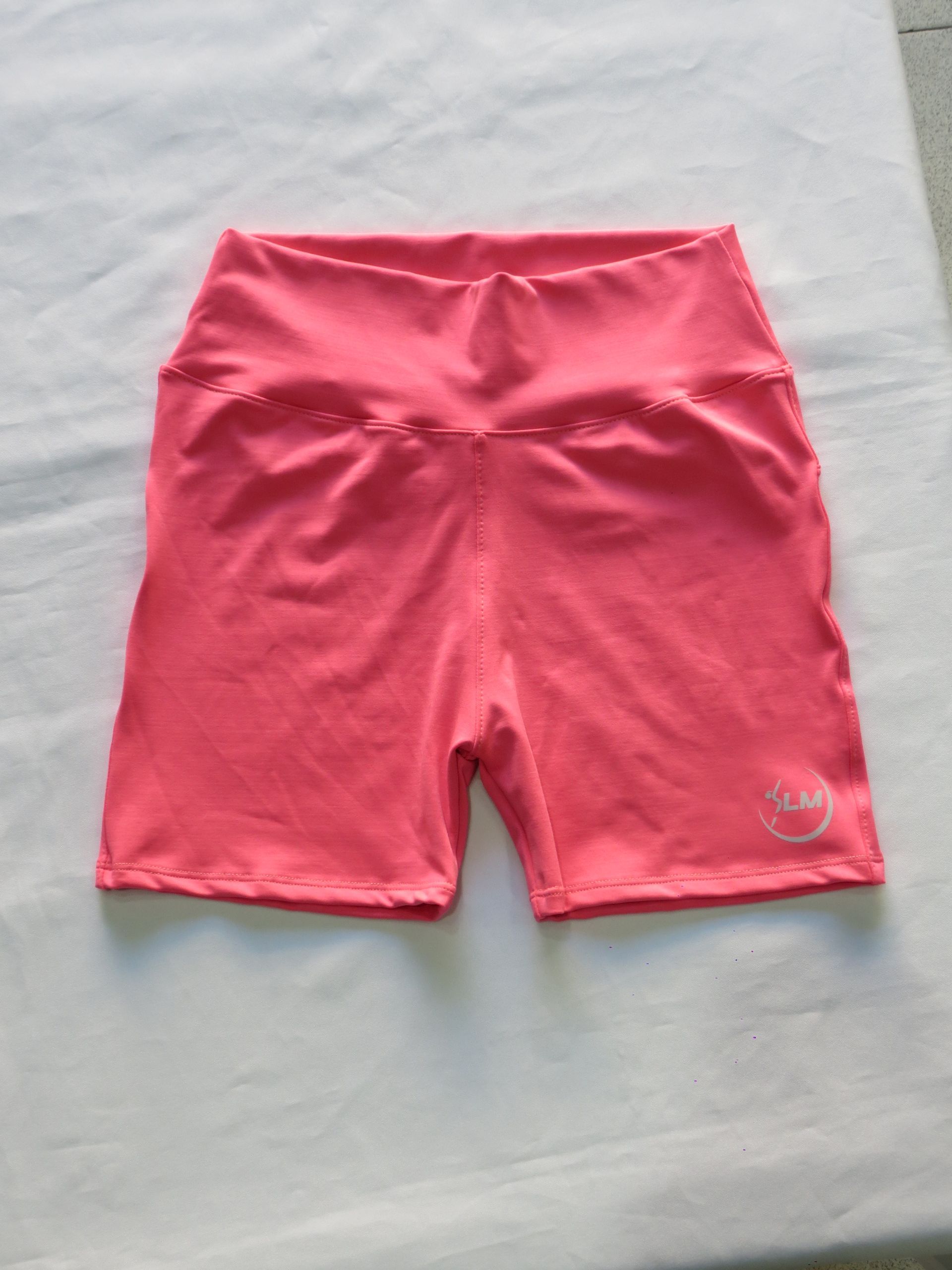 Shorts ciclistas de cintura alta de color rosa con un pequeño logo sobre fondo blanco.