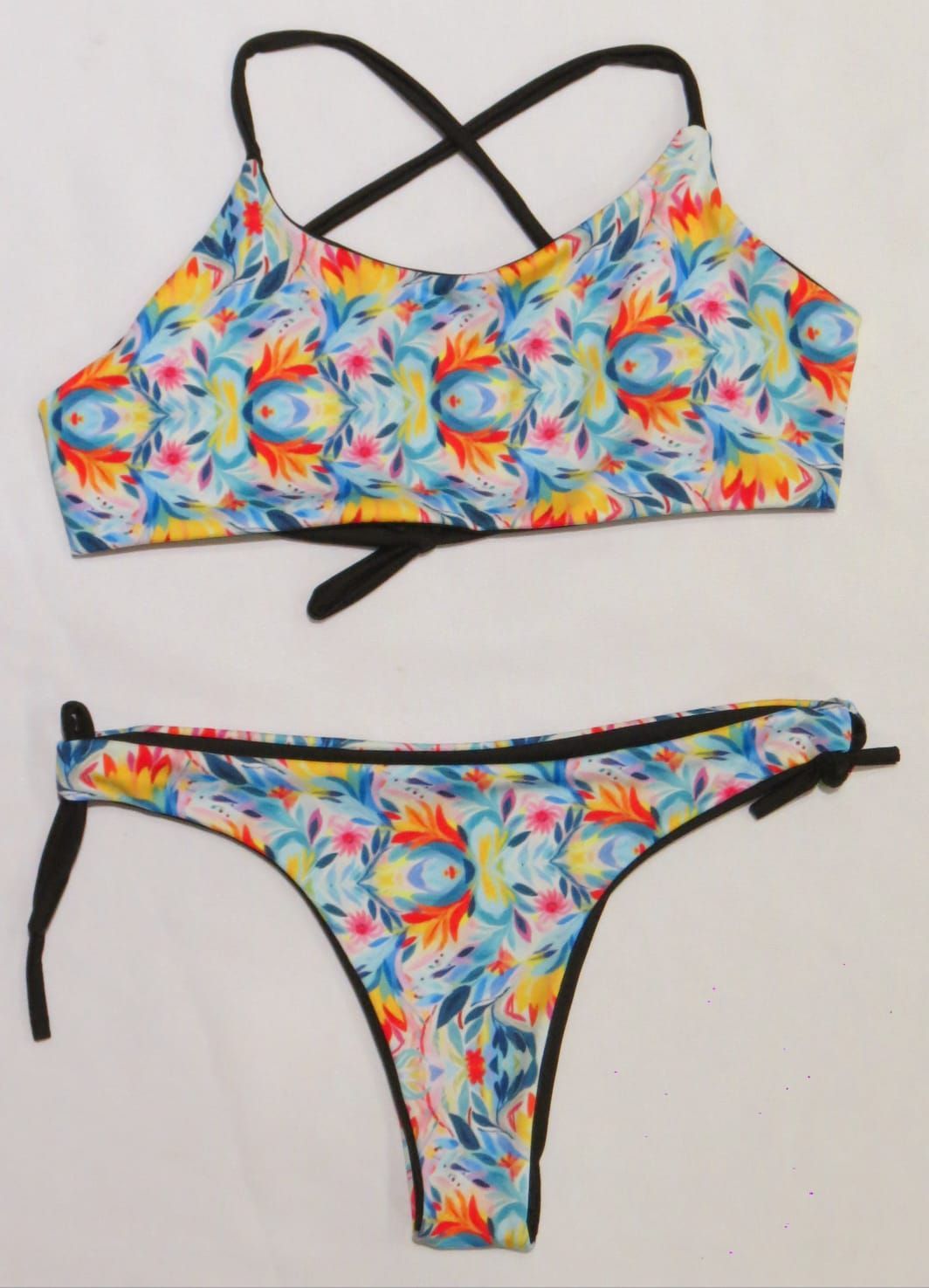 Parte superior e inferior de bikini con estampado floral colorido y ribete negro.