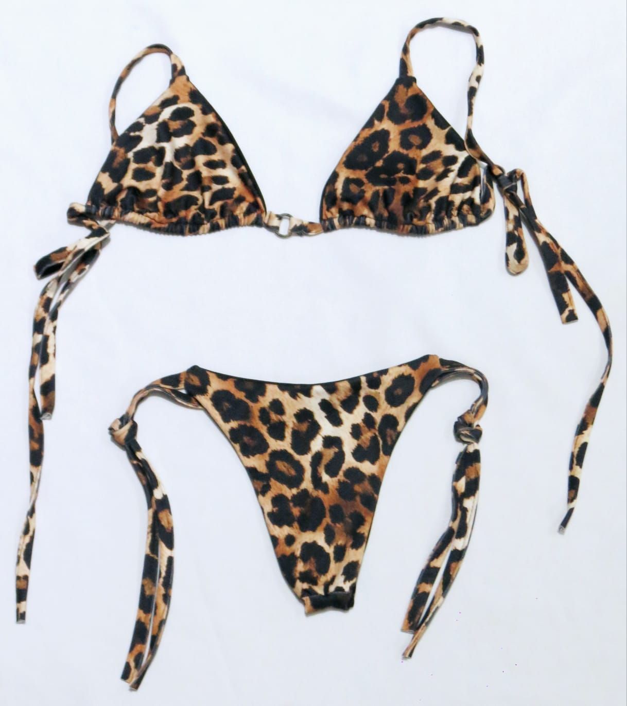 Top y braguita de bikini con estampado de leopardo sobre fondo blanco.