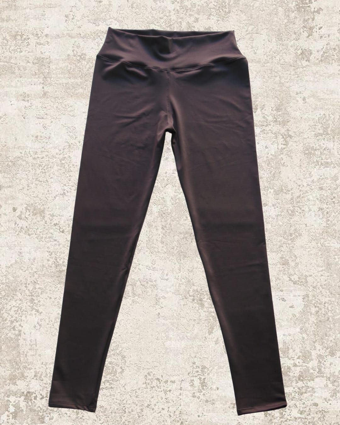 Leggings marrones de cintura alta sobre un fondo de textura neutra.