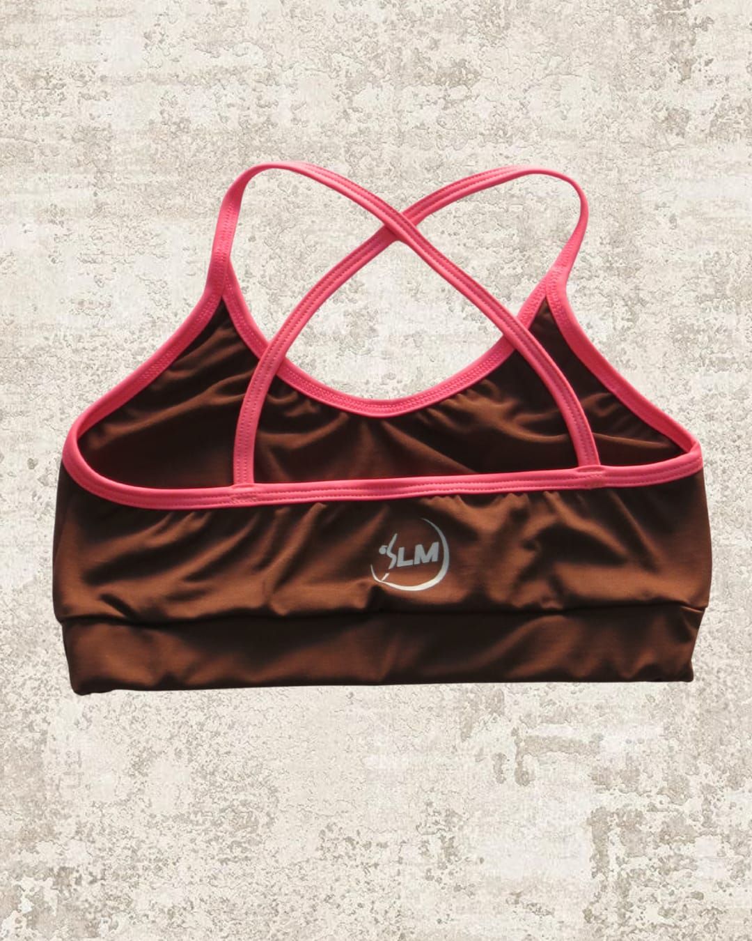 Sujetador deportivo marrón con tirantes rosas cruzados en la espalda.