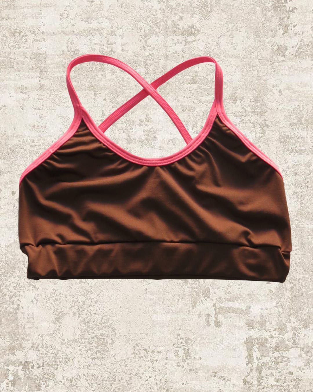 Sujetador deportivo marrón con ribete rosa y tirantes cruzados.