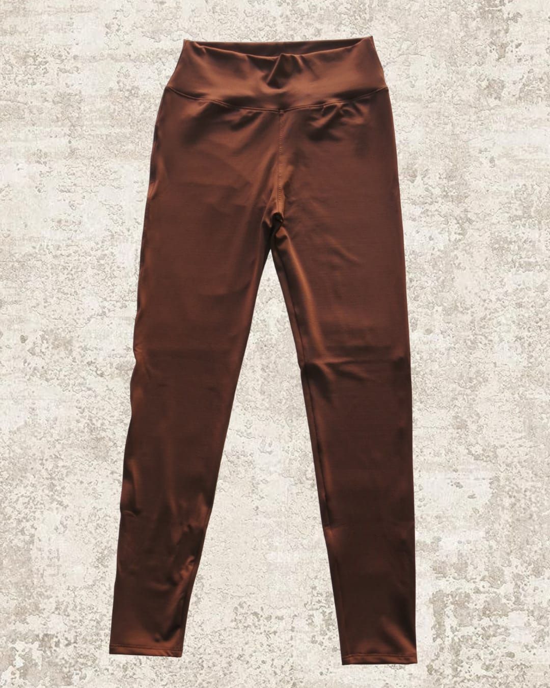 Leggings marrones sobre fondo neutro texturizado. Cintura alta.