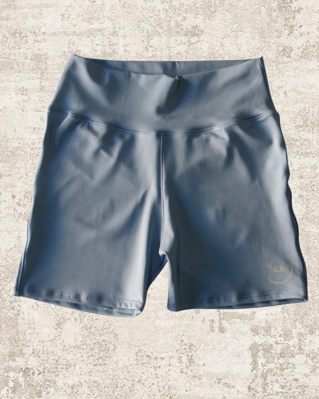 Pantalón corto deportivo de color azul claro sobre superficie texturizada.