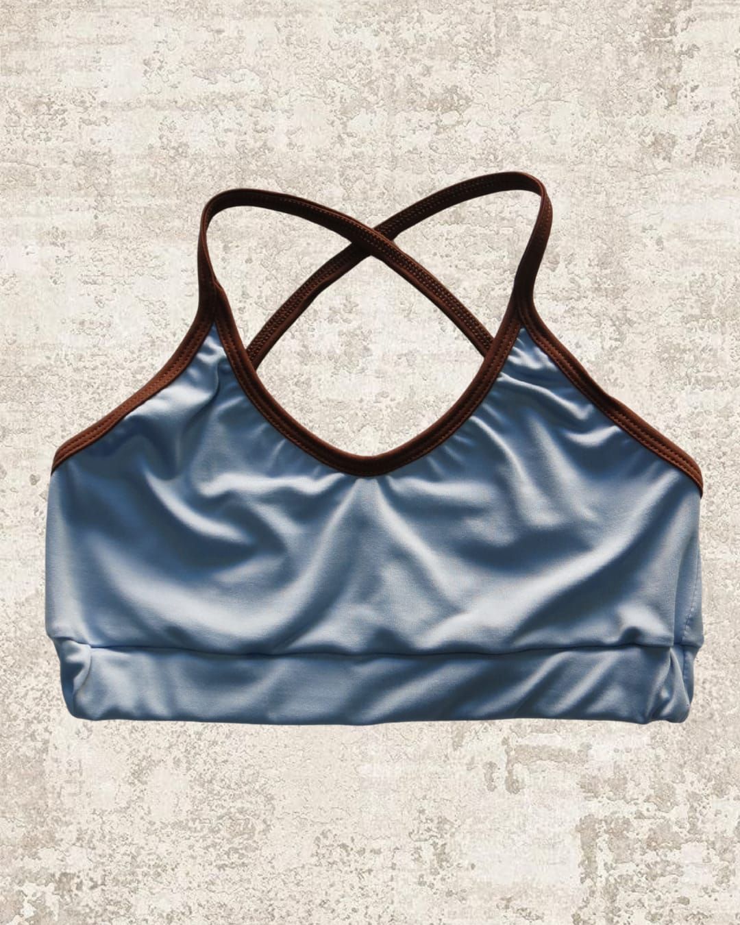 Sujetador deportivo azul con ribete marrón y tirantes cruzados.
