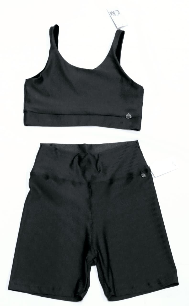 Conjunto de sujetador deportivo y pantalones cortos de color verde oscuro, expuestos sobre una superficie plana.