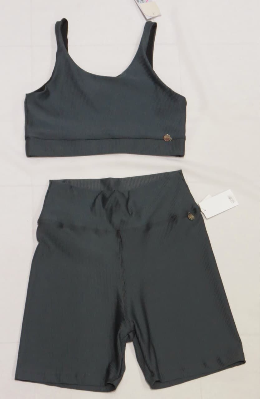 Conjunto de sujetador deportivo y pantalones cortos de color verde oscuro, expuestos sobre una superficie plana.
