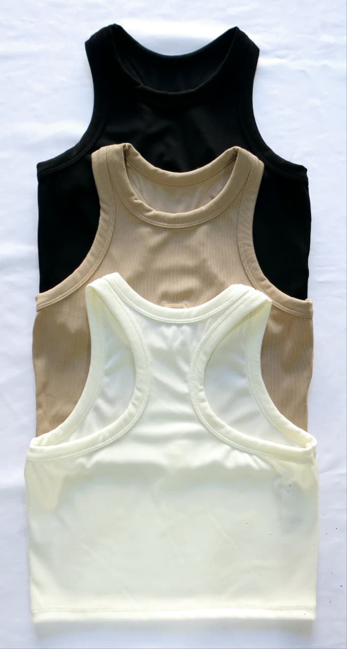 Tres camisetas sin mangas apiladas: negra, tostada y color crema.