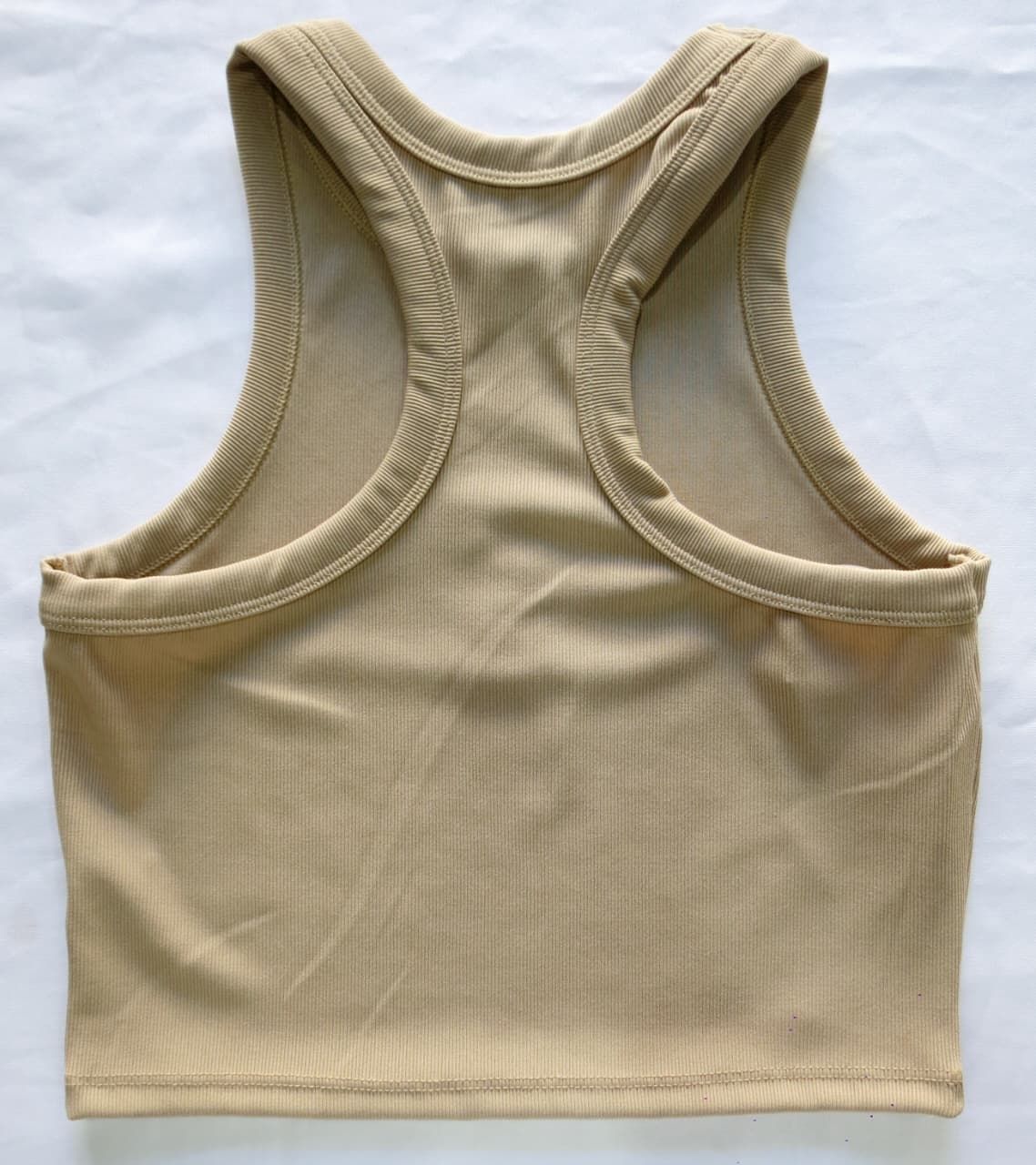 Top corto de canalé en color tostado con diseño de espalda deportiva.