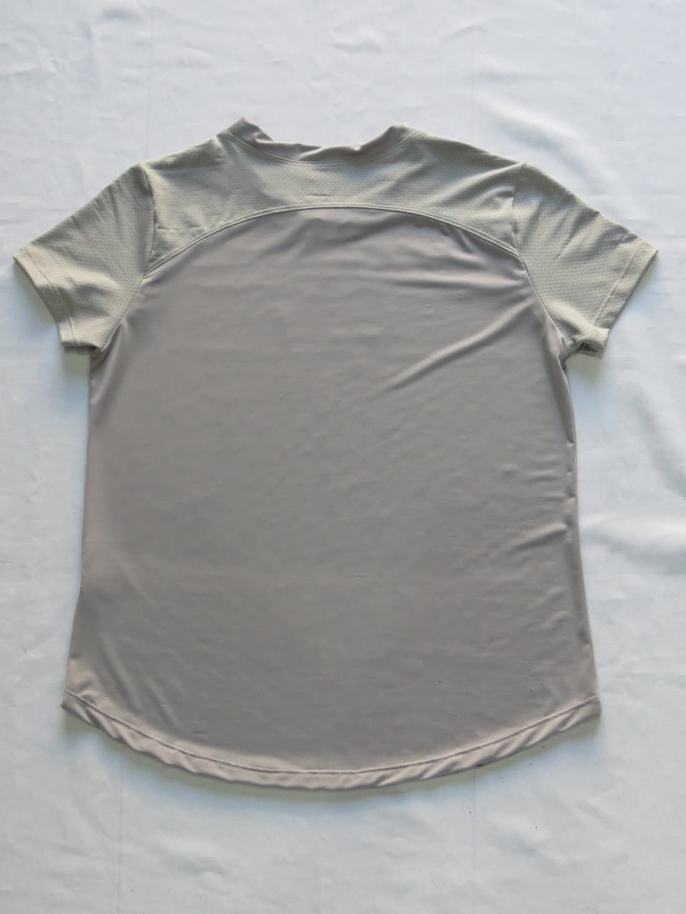 Camiseta gris de manga corta y bajo redondeado. Pequeño texto 