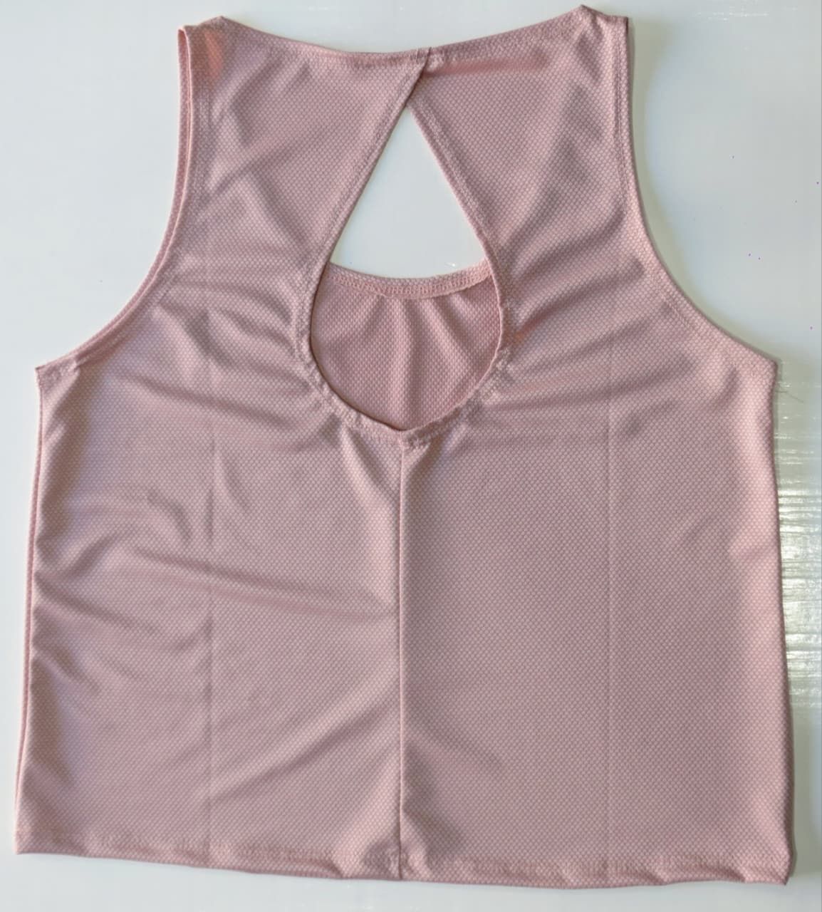 Camiseta deportiva rosa sin mangas con abertura en la espalda.