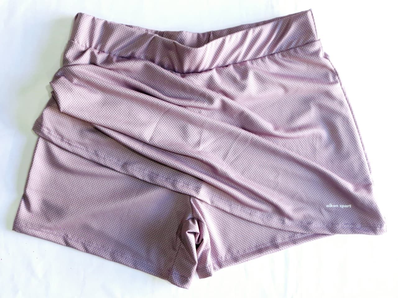 Pantalón corto deportivo de color rosa con diseño de falda superpuesta, probablemente para hacer deporte.