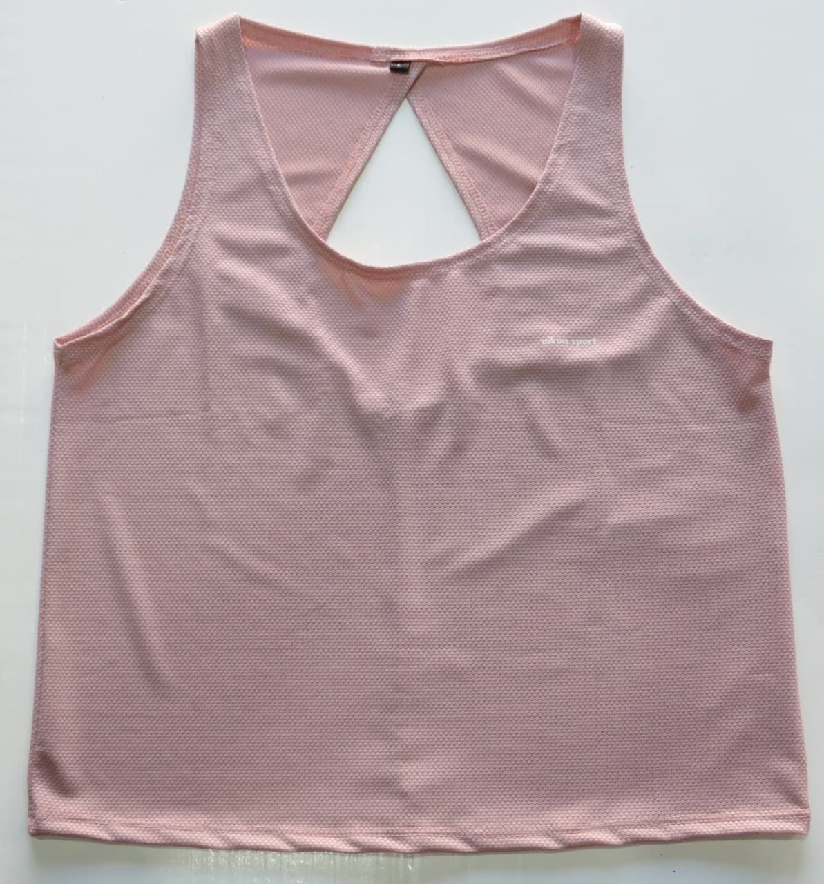 Camiseta deportiva sin mangas de color rosa claro con abertura triangular en la espalda.