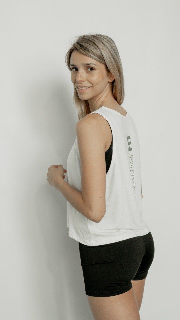 Una mujer vestida con ropa deportiva sonríe por encima del hombro: