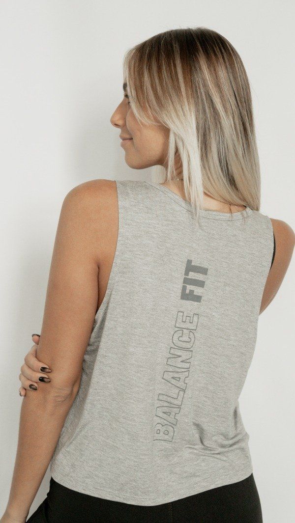 Mujer con camiseta gris, de espaldas a la cámara, con el brazo cruzado y la frase 