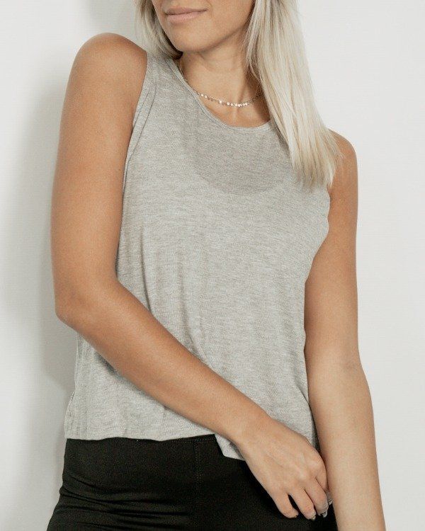 Mujer con una camiseta gris, sonriendo, en el interior.