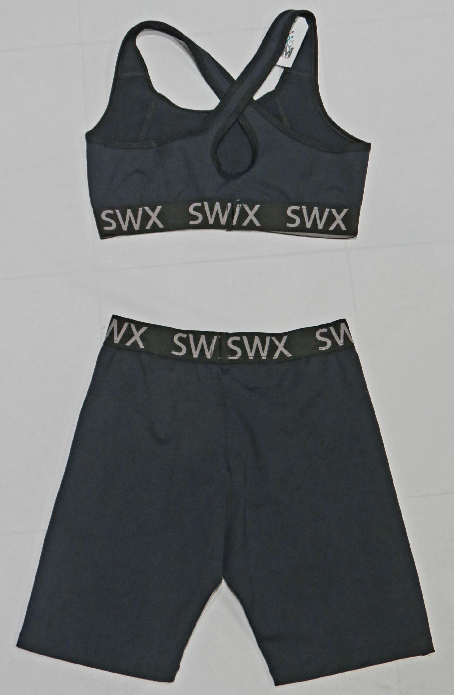 Conjunto de sujetador deportivo y pantalones cortos negros con logotipo SWIX en la cinturilla.