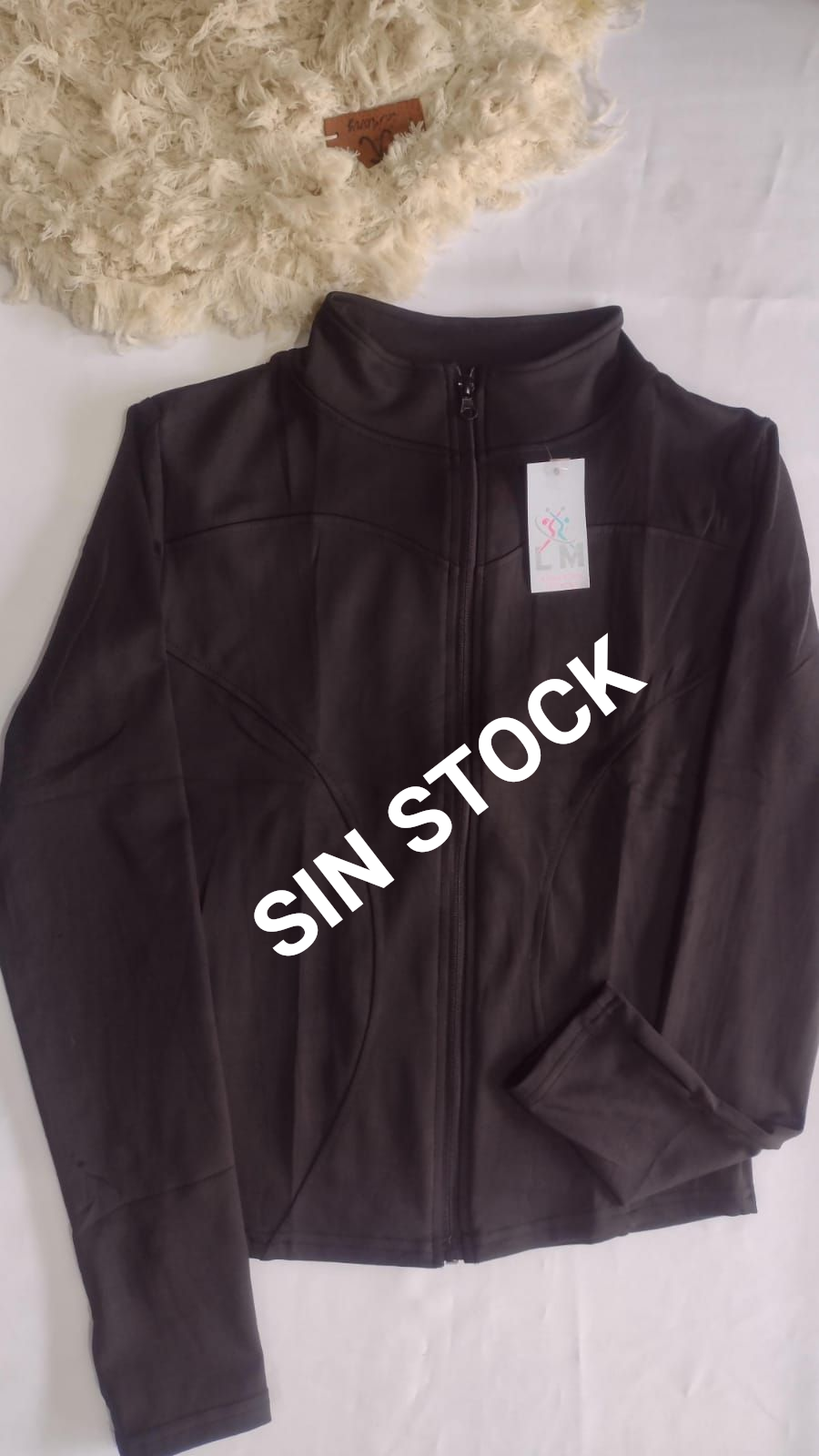 Chaqueta marrón oscuro con cremallera, sobre una superficie blanca.