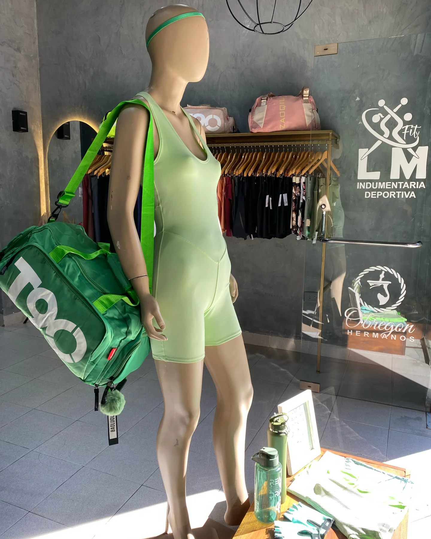 Un maniquí sostiene una bolsa de lona verde en una tienda.