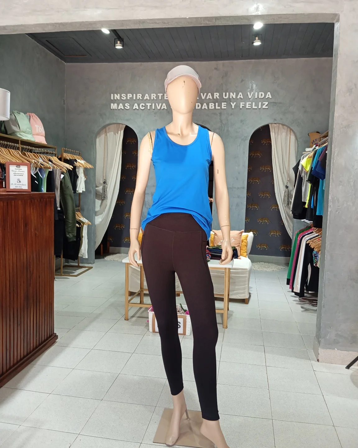 Un maniquí con una camiseta azul sin mangas y leggings marrones.