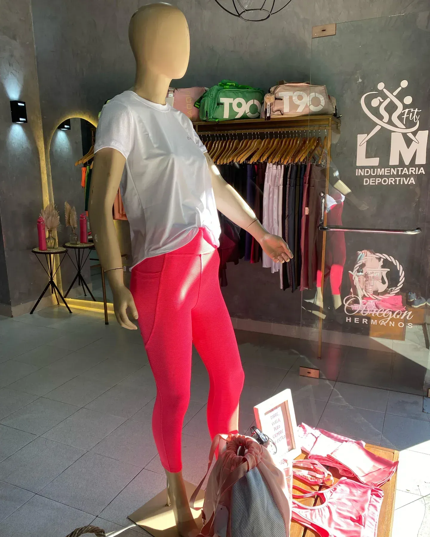 Un maniquí lleva una camisa blanca y pantalones rosas en una tienda.