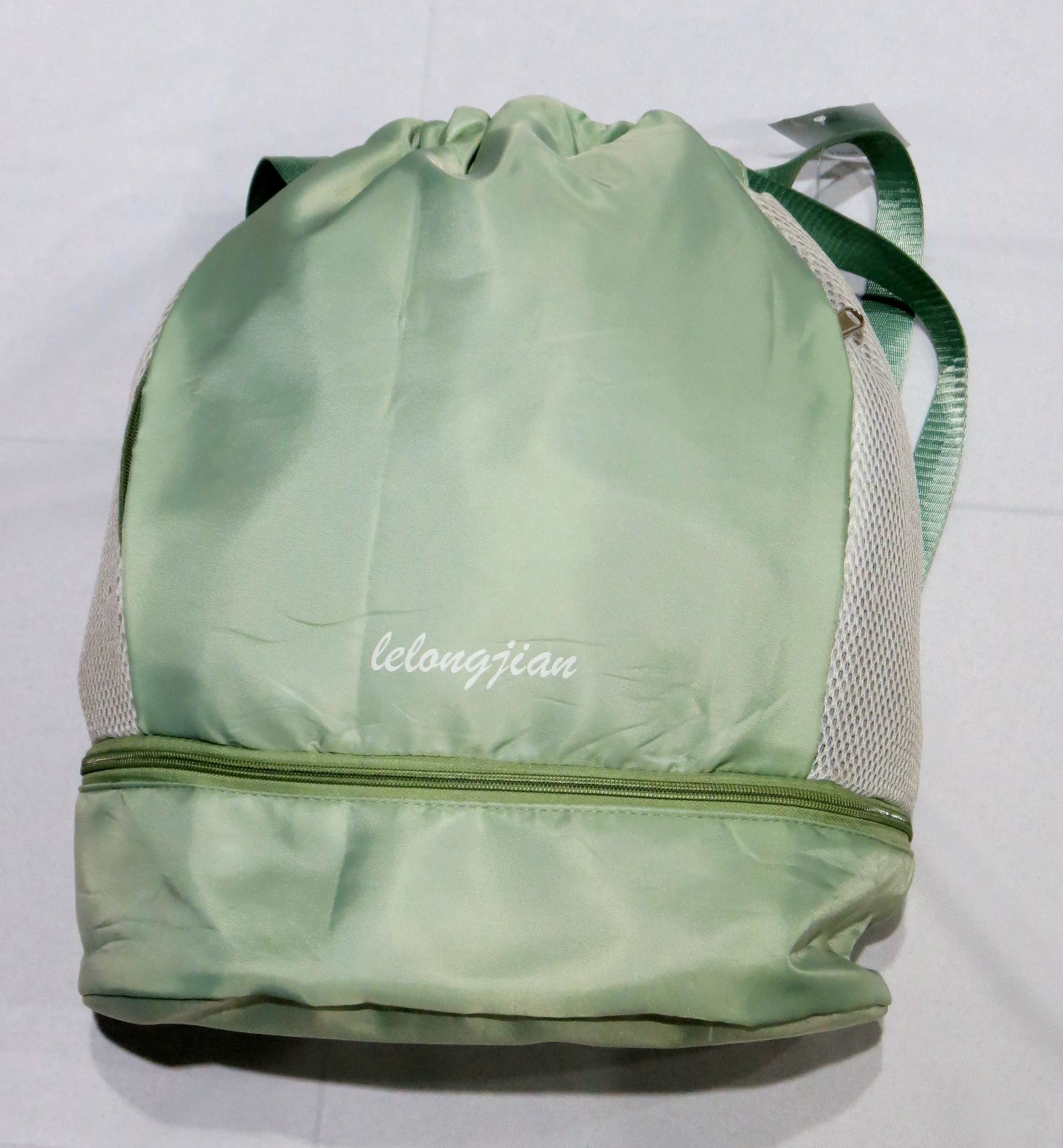 Bolsa con cordón de color verde claro, laterales de malla y asa verde.