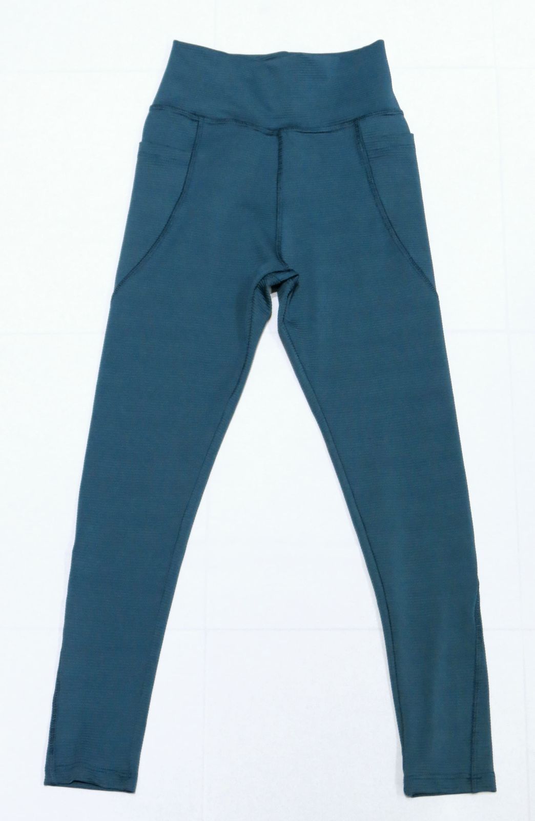 Leggings deportivos de color verde azulado con cintura alta y bolsillos laterales.