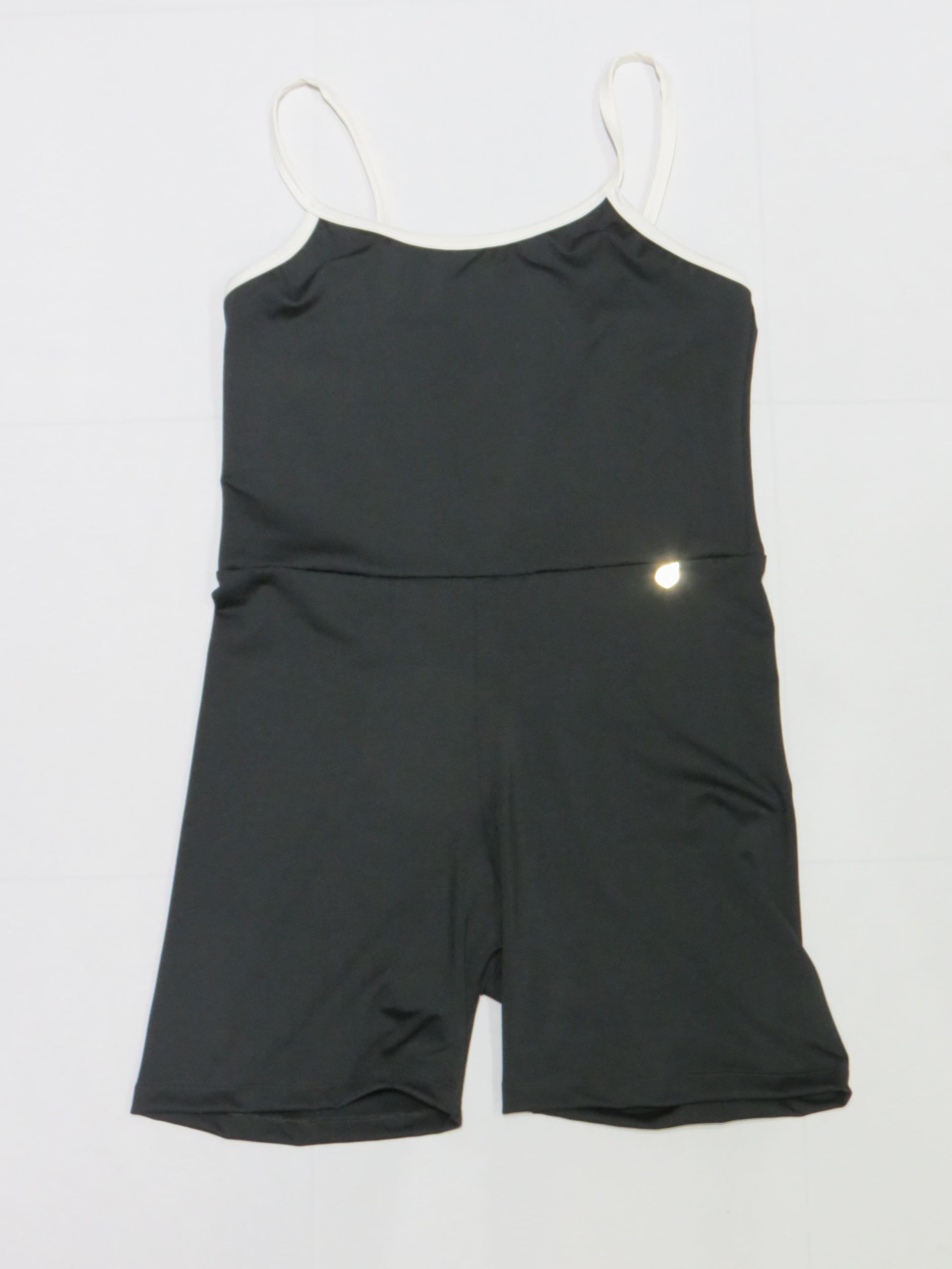 Mono deportivo negro con tirantes finos, pantalón corto y un pequeño logotipo reflectante.