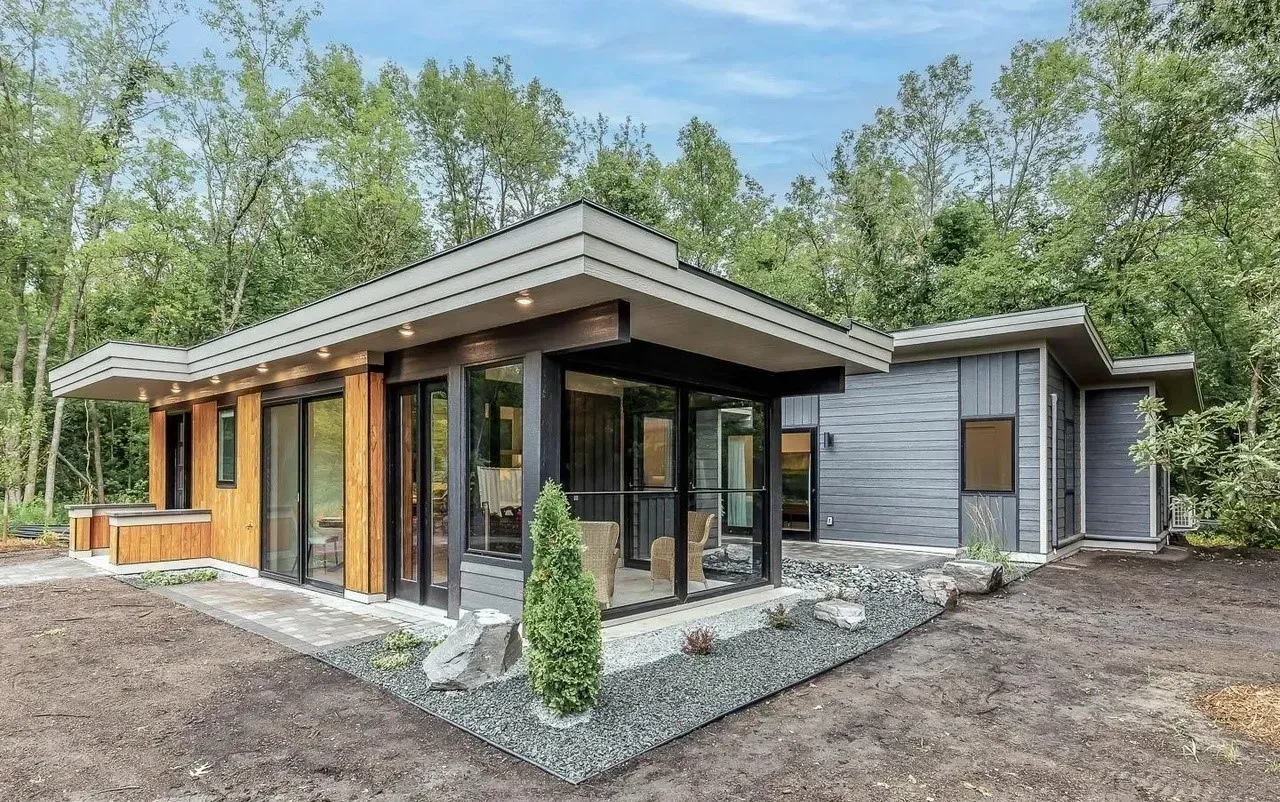 Modern home with a dark gray exterior, large windows, and a light-colored wood accent.
