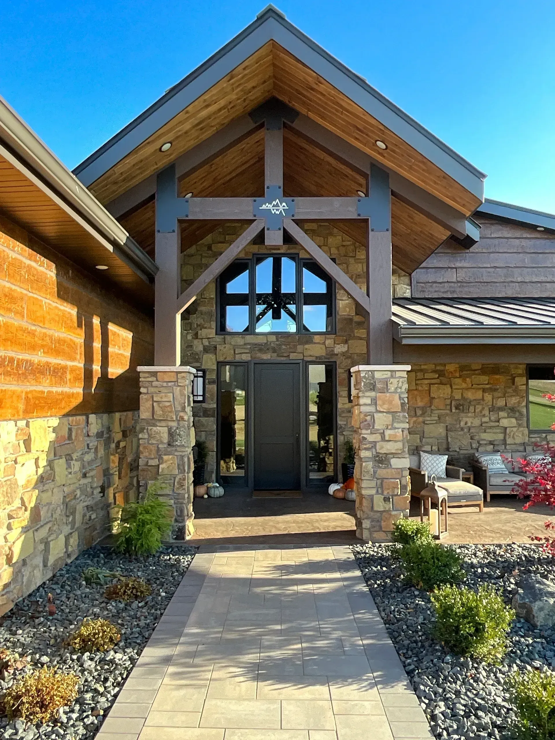 Entryway of a house with stone pillars and a wood-beamed roof over a dark door.
