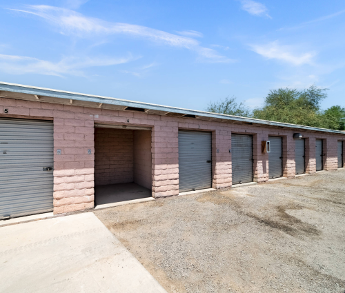 Row of pink brick storage units with gray doors under a blue sky.