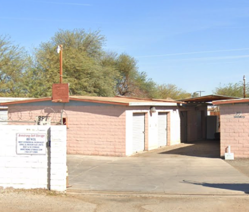 Pink storage units with white doors and a concrete drive in front.