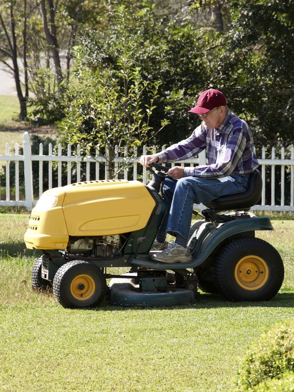 a man is riding a yellow lawn mower on a lush green lawn