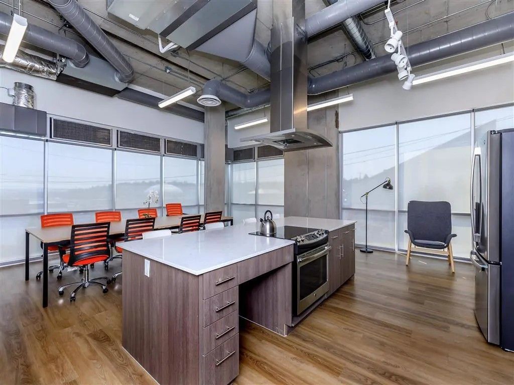 Modern kitchen with large island, stove, dining table, and windows.