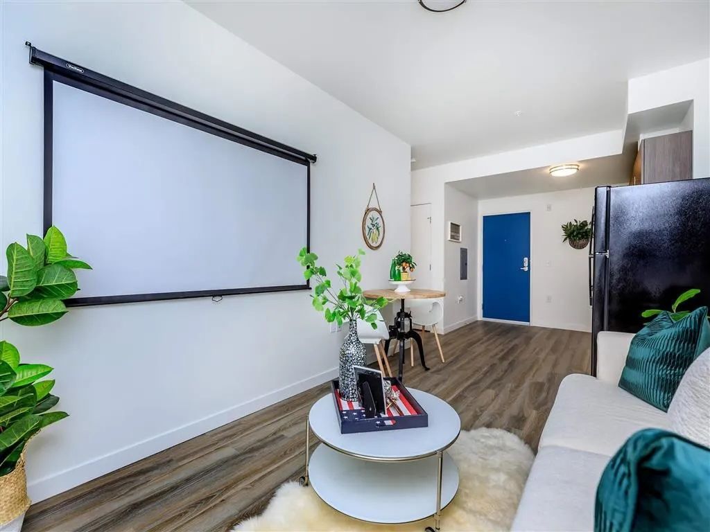 Living room with projector screen, small dining table, and white sofa.